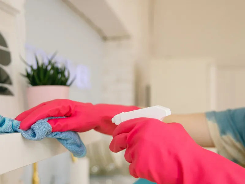 Schoonmaken met roze handschoenen en spray